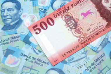 Kırmızı bir Macar beşyüz kırk banknotunun yakın plan resmi. Arka planda yirmi peso Meksika banknotları var.