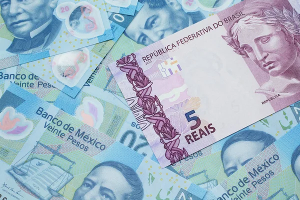 Brezilya 'dan gelen pembe bir 5 reais banknot Meksika pesolarının arka planında makroya yakın.