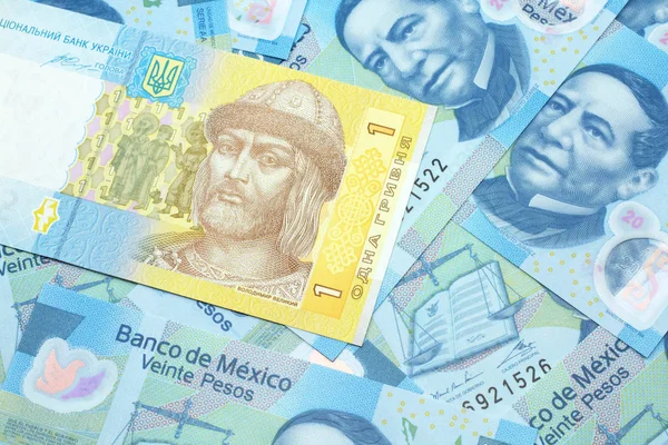 一张蓝色和黄色的乌克兰格里夫尼亚钞票在一张20比索墨西哥纸币的床上 — 图库照片