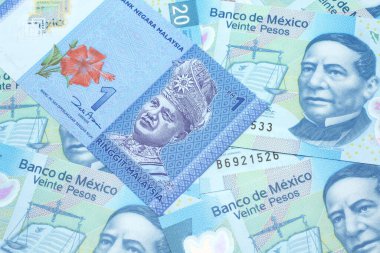 Meksika banknotlarından oluşan bir yatağın üzerinde mavi bir Malezya bankasının yakın plan resmi. Makro boyutta 20 peso.