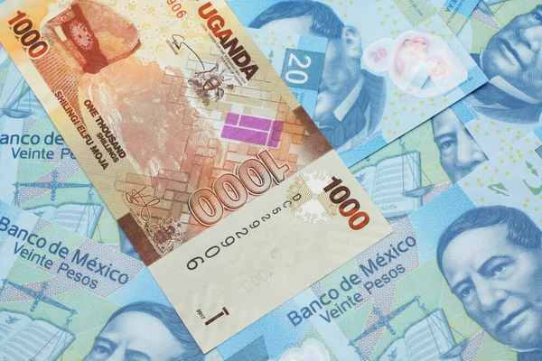 Zbliżenie Wizerunek Kolorowego Szylinga Ugandyjskiego Banknotu Meksykańskimi Dwudziestoma Peso Banknotami — Zdjęcie stockowe