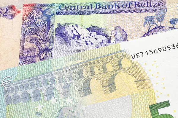 青と緑の5ユーロ ヨーロッパの銀行券と近いマクロでベリーズからカラフルな2ドル札 ストックフォト