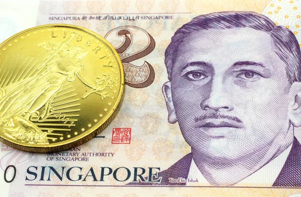 A macro image of a Singapore two dollar bill with a gold coin.  Shot close up.