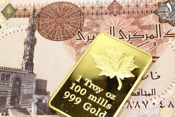 A macro image of a one pound Egyptian pound note with a gold bar.  Shot close up.