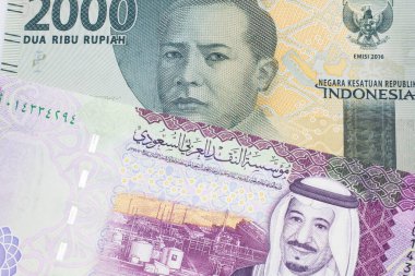İçinde beş Suudi riyal notu olan gri bir Endonezya rupiah banknotu. 