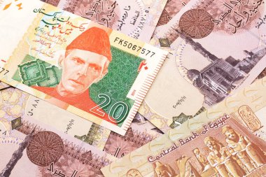 Gri ve pembe bir resim 20 Pakistan rupluk banknot ve bir pound 'luk makro banknot.