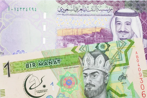 A green one manat note from Turkmenistan close up in macro with a five Saudi riyal bank note from Saudi Arabia\'s central bank