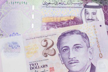 Suudi Arabistan 'daki 5 Suudi riyal banknotunun, Singapur' dan 2 dolarlık banknotla yakın plan fotoğrafı.