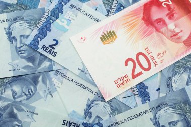 İsrail 'den gelen yirmi İsrail şekeli banknotun yakın plan resmi makrodaki iki Reais banknotunun arka planında.