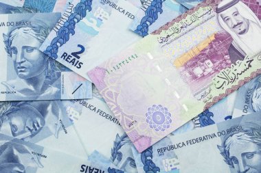 Brezilya bankasının arka planında Suudi Arabistan 'dan gelen beş riyal banknotunun yakın plan görüntüsü makroda iki reais banknot.
