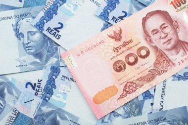 Tayland 'dan gelen kırmızı, 100 baht' lık bir banknotun yakın plan görüntüsü, makroda iki reais banknot.