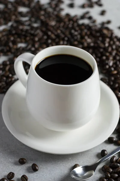 White glass of coffee with coffee bean on a stone table.