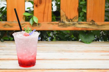 Çilekli İtalyan gazozu, kelebek bezelyesi çiçekli, plastik bardakta, ahşap masada..