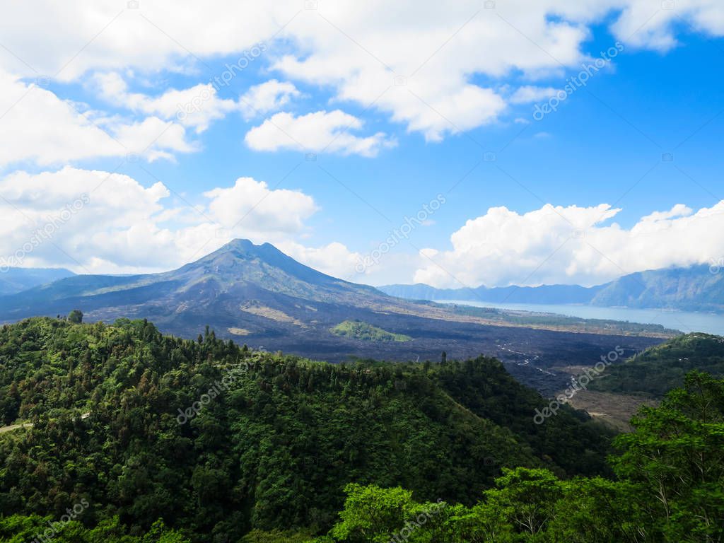 Volcano mountain view with lake, lush green forest, blue sky and