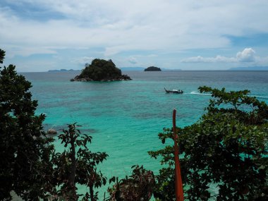 Güneşli bir gün yeşil ağaç yaprakları ile uzun kuyruklu tekne, küçük ada ve mavi gökyüzü yaklaşıyor ile turkuaz deniz manzarası