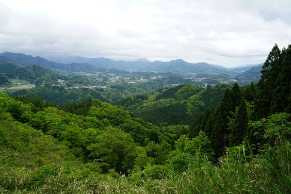 Paisaje de montaña verde y vista de la ciudad desde lejos —  Fotos de Stock