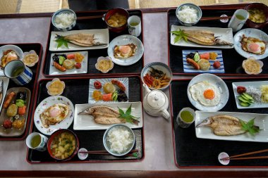 Japon Aile yanı konaklama kahvaltı dahil olmak üzere tepsi pişmiş pirinç, ızgara balık, sahanda yumurta, tofu çorbası, sosis, turşu, deniz yosunu, natto, diğer yan yemekler ve yeşil çay 