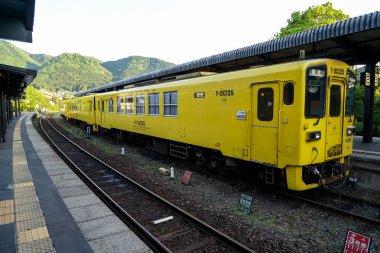 Yufuin, Japonya - 13 Mayıs 2017: sarı renk vintage tren Dizel araba Jr Kyushu demiryolu şirketinin durdu dağ panorama görünümü arka plan ile tren istasyonunda Ray üzerinde 