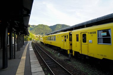 Yufuin, Japonya - 13 Mayıs 2017: sarı renk vintage tren Dizel araba Jr Kyushu demiryolu şirketinin durdu demiryolu tren istasyonu platformu dağ panorama görünümü arka plan ile