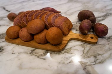 Gerçek tatlı patates dekorasyonu ile beyaz mermer üst üzerinde ahşap kesme tahtasında dilimlenmiş somun ve çörekler taze ev yapımı pişmiş mor Japon tatlı patates ekmek