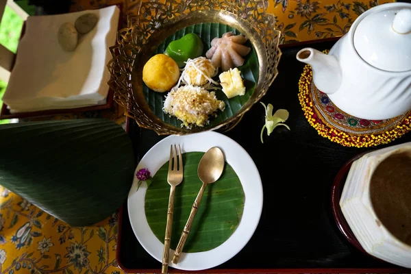 Afternoon tea time set of Thai traditional dessert with banana leaf and flower decoration on floral pattern table cloth — Stock Photo, Image