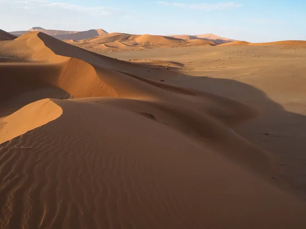 Walking on natural curved ridge line through wind blow pattern of rusty red sand dune with soft shadow on vast desert landscape horizon background, Sossus, Namib desert — Stock Photo, Image