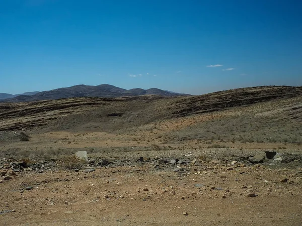 Yolculuğa araba lastik ile zorlu tozlu asfaltsız yol aracılığıyla takip aracılığıyla kuraklık çöl iklim ve hard rock dağ manzarası açık mavi gökyüzü ve kurutulmuş bitki