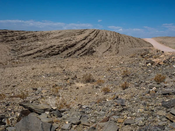 Podróż przez skały góry suszony tło zakurzone krajobraz Pustyni Namib z podziału łupkowego kawałki, inne kamień, pustynia roślina i błękitne niebo — Zdjęcie stockowe