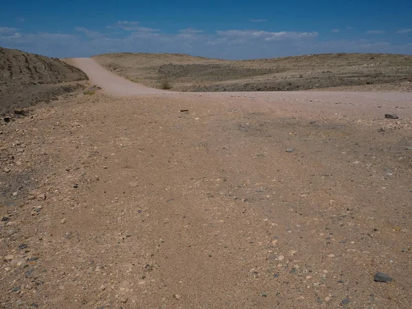 Kuru Tozlu rock dağ manzara zemin taş ve mavi gökyüzü ile Namib Çölü arka plan ile kumlu yolculuğa boşaltmak