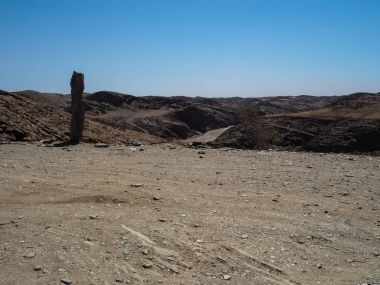 Offroad yolculuk boyunca büyük rock dağ manzara arka plan Namib Çölü benzersiz coğrafyasının taşlı zemin yol, çöl bitki ve açık mavi gökyüzü