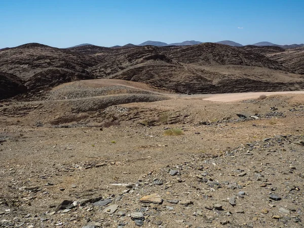 Doğal taş dağ doku Namib Çölü benzersiz coğrafyasının taş kumlu zemin, çöl bitki ve mavi gökyüzü bölme ile arka plan manzara