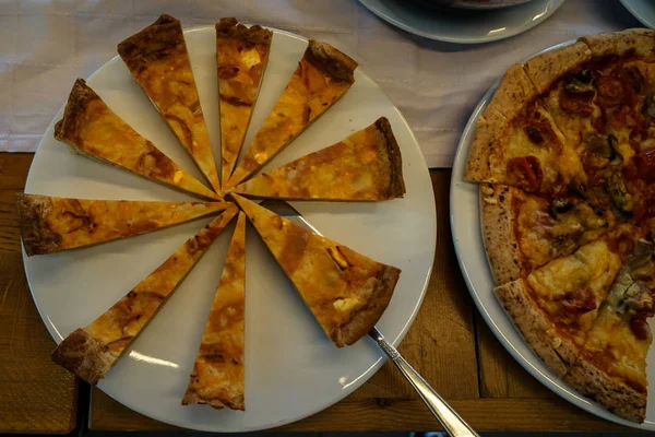 ギリシャの朝食ビュッフェ テーブルにピザの部分と白い皿の上の自家製の焼きたてのパイのおいしいスライス — ストック写真