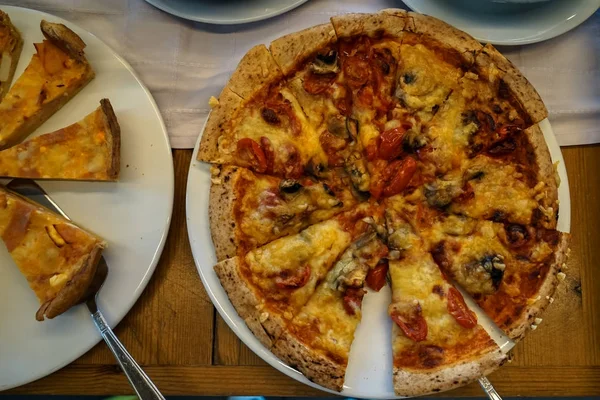 Deliciosa fatia de pizza caseira assada em prato branco com parcial de tortas na mesa buffet de café da manhã grego — Fotografia de Stock