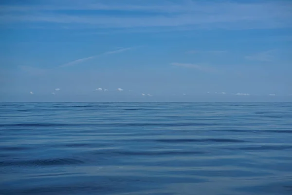 明るく青い空地平線と深い青色の海の水の波紋凍結の動きの上の白い雲の自然な背景シーン — ストック写真