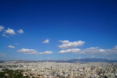 Lowrise beyaz binalar, dağ, ağaçlar, beyaz bulut ve parlak mavi gökyüzü arka plan gösterilen Atina cityscape bakış