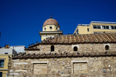 Eski klasik küçük kilise güvercinler üzerinde pişmiş toprak kiremit ile açık mavi gökyüzü ile toprak tonlarda doğal taş ve modern arka bina