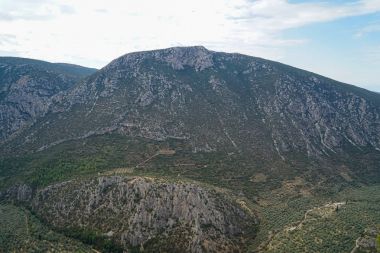 Taze manzara parlak gökyüzü arka plan ile Parnassos kireçtaşı dağ Vadisi, yeşil zeytin ağaçlarıyla görünümünü çevreleyen