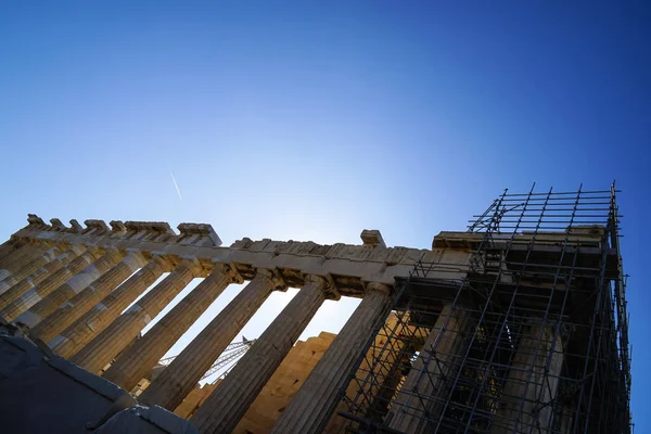 Restoration work in progress at world heritage ancient Parthenon showing Doric order on top of Acropolis with scaffolding and blue sky background