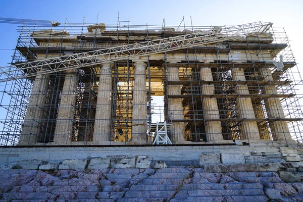 Restoration work in progress at world heritage ancient Parthenon on marble base on top of Acropolis with machine crane,  scaffolding and blue sky background — Stock Photo, Image