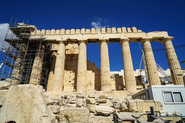 Restoration work in progress at world heritage classical Parthenon on marble block base on top of Acropolis with site office, scaffolding and blue sky background