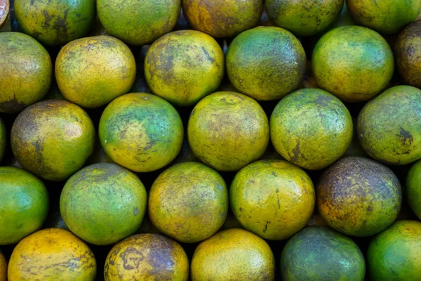 Montón de fruta fresca tailandesa local orgánica de mandarina fondo naranja en color amarillo, verde y textura marcada de la piel que se vende en el mercado — Foto de Stock