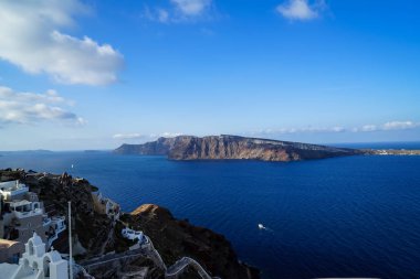 Büyük mavi Ege Denizi, yelkenli gemiler ve doğal caldera dağ boyunca ada ve mavi gökyüzü arka plan beyaz binalar ile Oia köyden güzel panoramik manzaralı