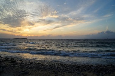 Güzel bir günbatımı manzara dalgalı deniz manzaralı ve yumuşak turuncu ve mavi gökyüzü ve soyut bulut arka plan güzel tonlarında doğal kaya Plajı 