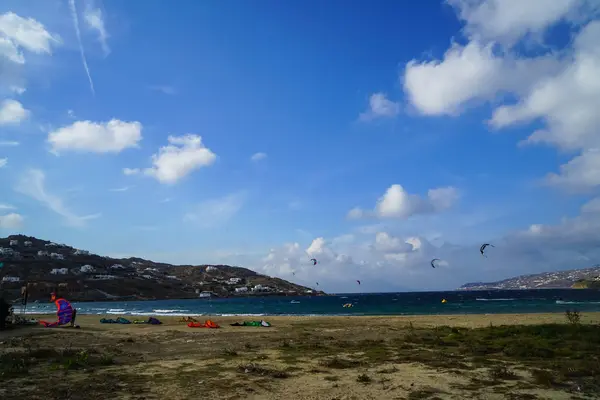 Mykonos, Grecia - 28 settembre 2017: Kitesurf, una specie di sport acquatici estremi in forte vento per l'attività di windsurf sulla spiaggia della baia di Korfos con sfondo di montagna e cielo blu , — Foto Stock