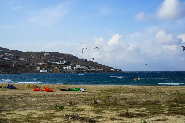 Mykonos, Grecia - 28 settembre 2017: Kitesurf, tipo di windsurf estremo imbarco sport acquatici colorati in forte vento sulla spiaggia della baia di Korfos con sfondo di montagna e cielo blu — Foto Stock