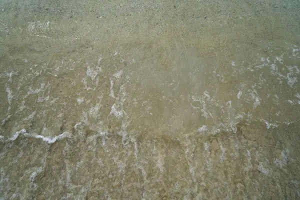 Zachte pastel zandstrand met verse zee water en witte schuimende Golf textuur en achtergrond op Ornos oever — Stockfoto