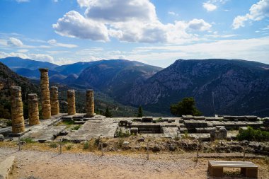 Eski harabe dünya mirası yeşil zeytin ağaçlarıyla Vadisi, Parnassos Dağı, mavi gökyüzü ve bulut beyaz arka plan ile Apollo Tapınağı, panoramik manzaralı
