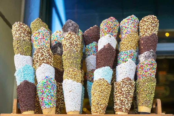 Full stacks of special colorful homemade cone decoration for ice cream with varieties of glazing including sprinkles, crushed almond and pistachio nut with blurred background