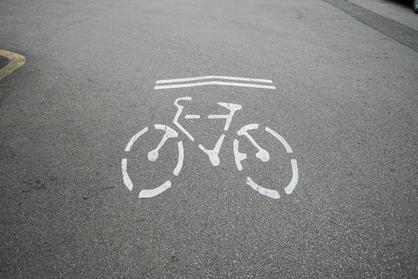Bike direction sign, environmental friendly symbol, in white on urban grey asphalt street surface