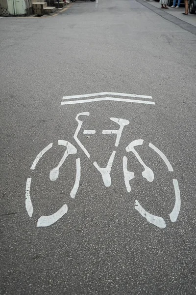Bicycle direction signage, environmental friendly symbol, in white on urban grey asphalt street surface